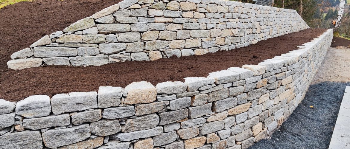 Terrassierte Natursteinmauer aus Hofer-Stein mit frischer Erde.