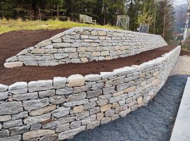 Terrassierte Natursteinmauer aus Hofer-Stein mit frischer Erde.