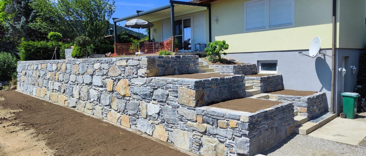 Mehrstufige Stützmauer aus blauem Schiefer in Beton verlegt.