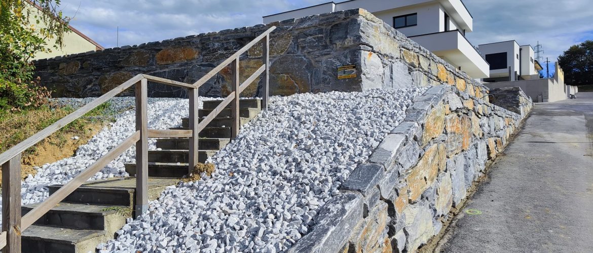 Stützmauer aus blauem Schiefer mit Treppe und Holzgeländer.