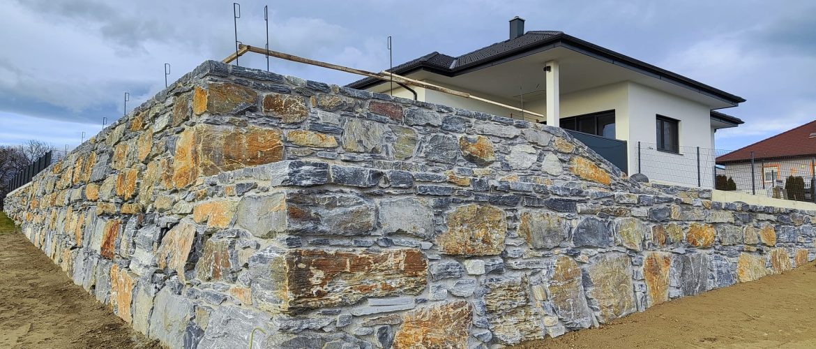 Mehrstufige Steinmauer aus blauem Schiefer mit Rampe vor modernem Haus.