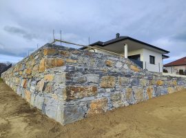 Mehrstufige Steinmauer aus blauem Schiefer mit Rampe vor modernem Haus.