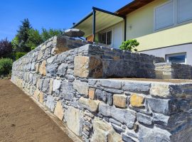 Hangsicherung mit Natursteinmauer aus Schiefer in einem Garten bei einem Einfamilienhaus