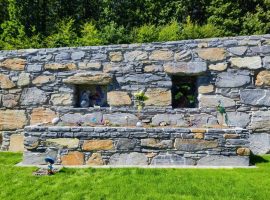 Natursteinmauer mit Nischen und vorgelagertem Hochbeet in einem Garten
