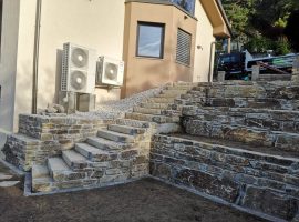 Stufenanlage aus Gneis mit Natursteinmauern auf zwei Ebenen in einem Garten